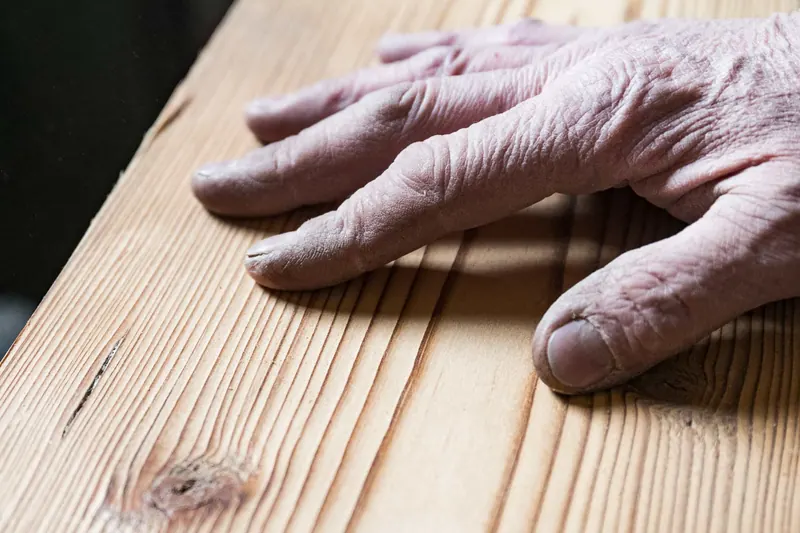Mano di un artigiano su una tavola di legno