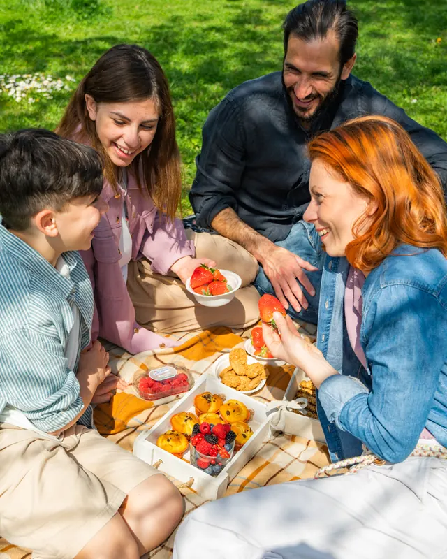 Famiglia che condivide dolci e frutti di bosco durante un picnic