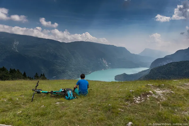 Mountain biker in pausa sopra un lago alpino