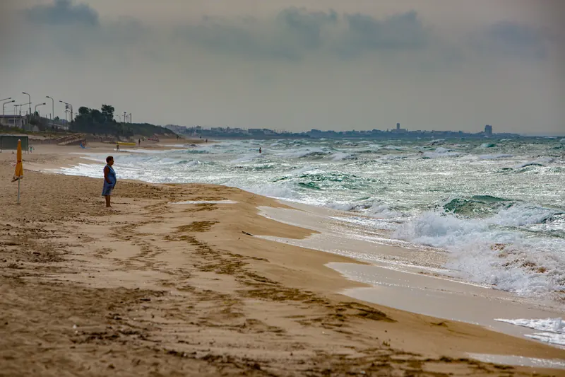 Bambina sulla spiaggia davanti al mare mosso
