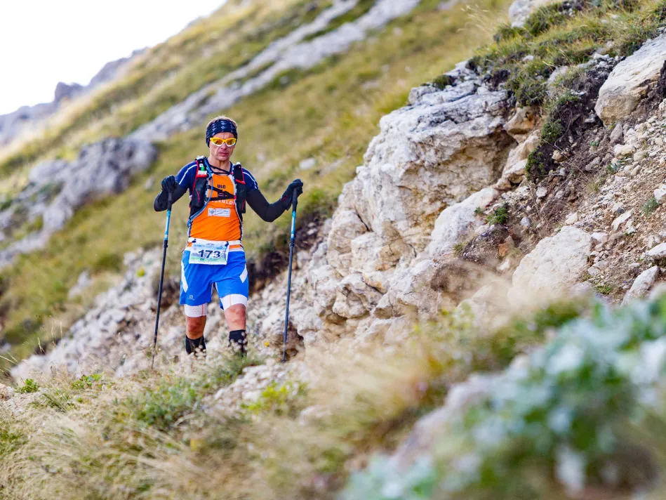 Atleta di trail running su sentiero roccioso al Passo Pordoi